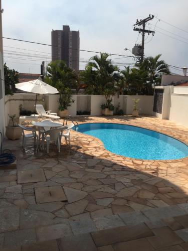 einen Pool mit einem Tisch und einem Sonnenschirm in der Unterkunft Hotel Riviera Lins in Lins