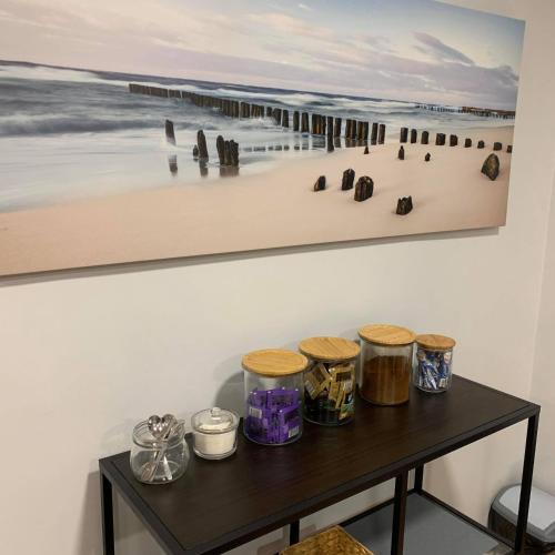 a table with jars and a painting on a wall at Przystanek Sopot Plaża in Sopot