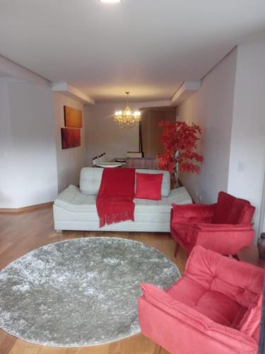 a living room with red chairs and a couch at Conforto em Campos in Campos do Jordão