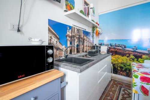 a kitchen with a sink and a mural of a building at Casa Dreaming Ortigia in Siracusa