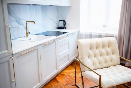 a white kitchen with a sink and a chair at APARTAMENTY ARTE LUBLIN Niecała 11 parking free in Lublin
