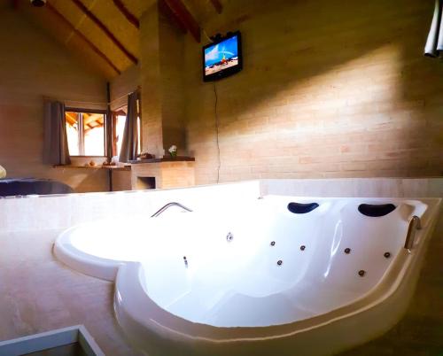 a large white tub in a room with a tv at Chalé na Montanha in Santo Antônio do Pinhal