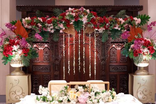 a table with flowers in front of a backdrop at HARRIS Hotel & Conventions Bundaran Satelit Surabaya in Surabaya