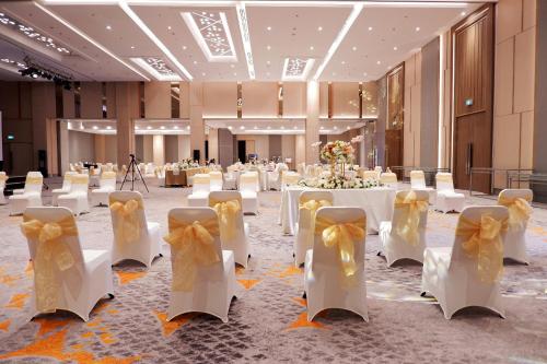 a banquet hall with white tables and yellow bows at HARRIS Hotel & Conventions Bundaran Satelit Surabaya in Surabaya