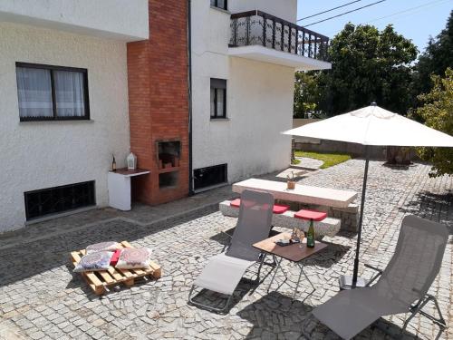 a patio with a table and an umbrella and chairs at Morada do Ultramar in Viana do Castelo