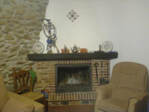 a living room with a fireplace and two chairs at Casa Amat in Rubite