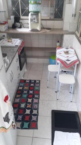 a kitchen with a table and two chairs and a rug at Pertinho da Mata in Cachoeiras de Macacu