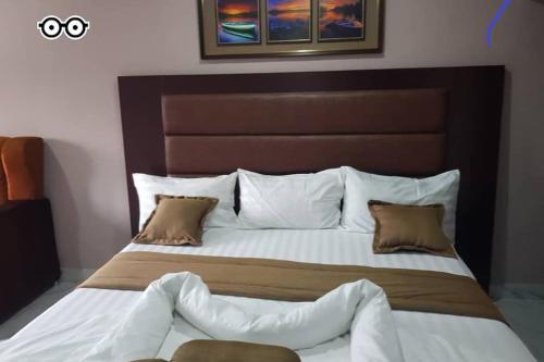 um quarto com uma cama grande com lençóis brancos e almofadas em ULOM 1condos apartment em Owerri