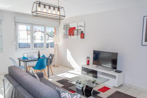 a living room with a couch and a tv at Le Victoria hyper-centre Décines in Décines-Charpieu
