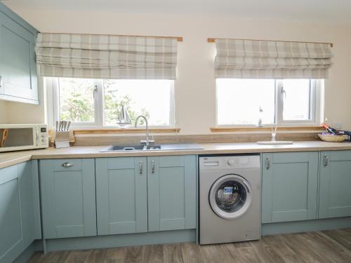 a kitchen with blue cabinets and a washing machine at 2 Whiterow in Powfoot