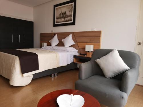 een slaapkamer met een bed, een stoel en een tafel bij Murano Hotel in Moyobamba