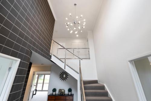 a staircase in a house with a chandelier at Rise and Shine - Taupo in Taupo