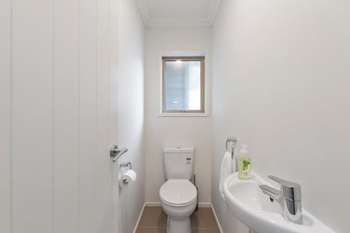 a white bathroom with a toilet and a sink at Rise and Shine - Taupo in Taupo