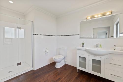 a white bathroom with a toilet and a sink at Rise and Shine - Taupo in Taupo