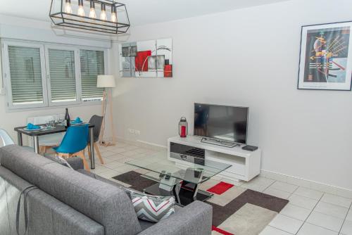 a living room with a couch and a tv at Le Victoria hyper-centre Décines in Décines-Charpieu