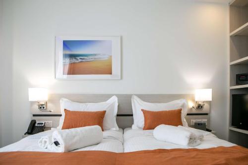 a bedroom with a large bed with white sheets and orange pillows at Best Western Plus Larco Hotel in Larnaka