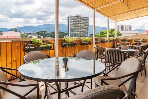 a patio with tables and chairs on a balcony at Hotel Palma Real in San José