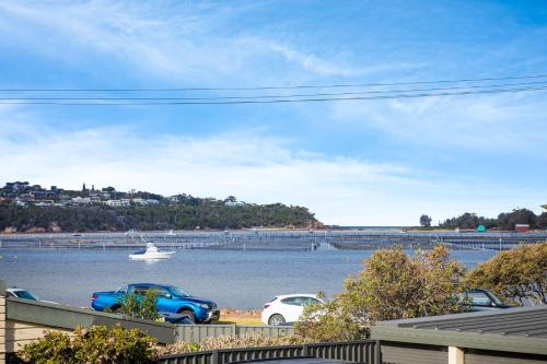 a boat in the water with two cars parked at Penguin Mews Merimbula in Merimbula