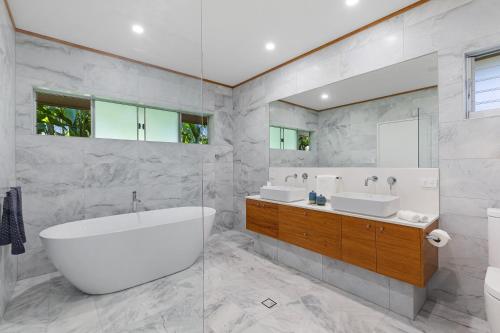 a bathroom with two sinks and a tub and a mirror at Celeste - at Funnel Bay in Airlie Beach