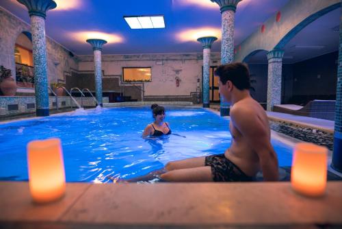 a man and a woman sitting in a swimming pool at Casanova - Wellness Center La Grotta Etrusca in San Quirico dʼOrcia