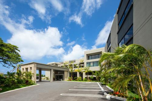 un edificio de oficinas con palmeras delante en Glamday Style Okinawa Yomitan Hotel & Resort en Yomitan
