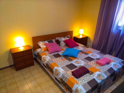 a bedroom with a bed with colorful pillows on it at Friends in Braga - Charming Bedrooms in the Historic Center in Braga