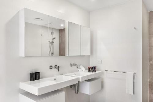une salle de bain blanche avec deux lavabos et un miroir dans l'établissement Ruby Gold Coast By Serain, à Gold Coast