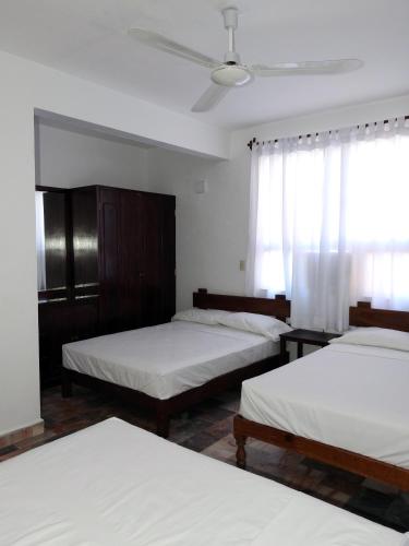 a bedroom with three beds and a ceiling fan at Don Luis Hostal - Sucursal Hidalgo - Tecolutla in Tecolutla