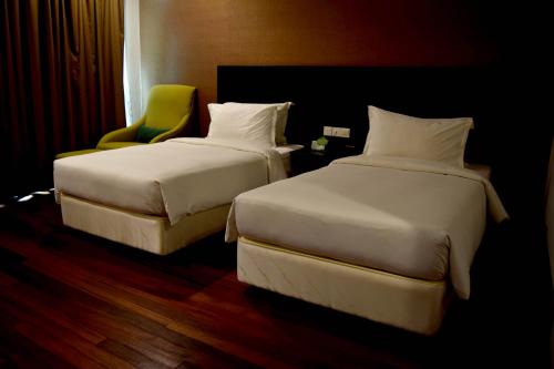 a hotel room with two beds and a chair at Lazenda Hotel in Labuan