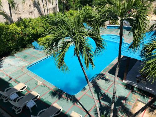 a swimming pool with palm trees and lounge chairs at La Gaviota A3 in Juan Dolio