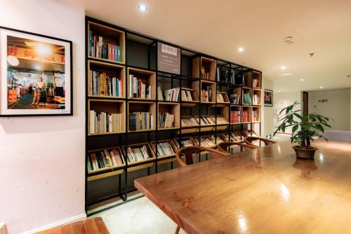 a library with a wooden table and chairs and bookshelves at Trip Voicer Chengdu Wide and Narrow Alley in Chengdu
