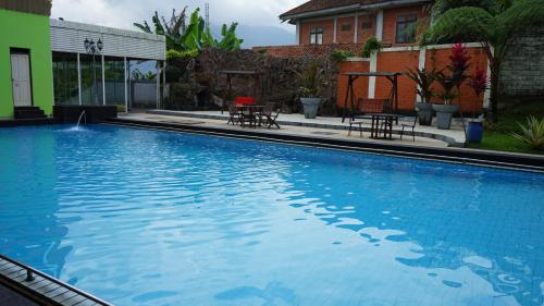 une grande piscine bleue à côté d'une maison dans l'établissement BRIA Hotel & Convention, à Bogor