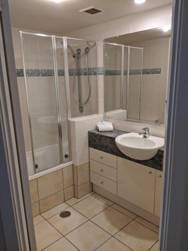 a bathroom with a sink and a shower and a toilet at Moorings Beach Resort in Caloundra