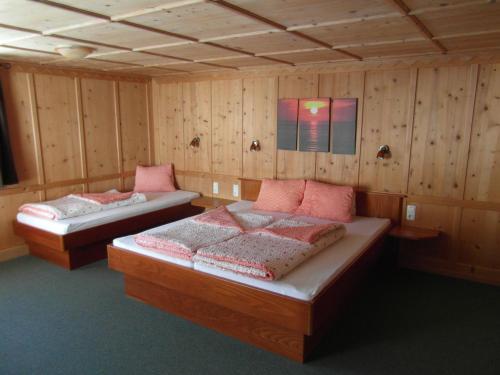 two beds in a room with wooden walls at Ferienhaus Nadine in Kappl