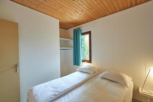 un lit dans une chambre avec une fenêtre dans l'établissement FranceComfort - Village des Cigales, à Mauroux