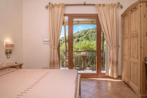 a bedroom with a bed and a large window at Hotel Aldiola Country Resort in Sant Antonio Di Gallura
