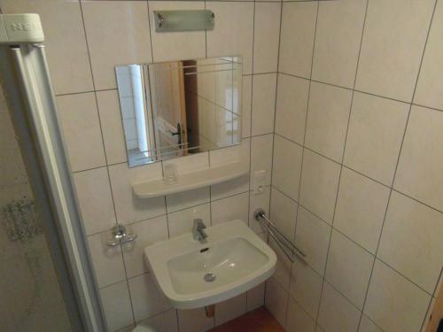 a white tiled bathroom with a sink and a mirror at Ferienhaus Nadine in Kappl