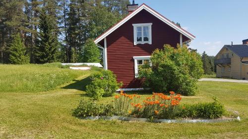 a red house with a flower garden in front of it at Hugsnäset Semesterstugor och Fiske in Gällö