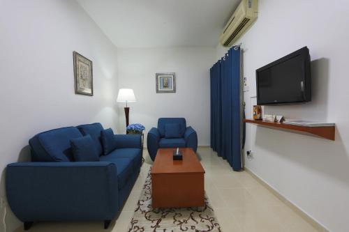 a living room with two blue couches and a tv at Nova Park Hotel in Sharjah