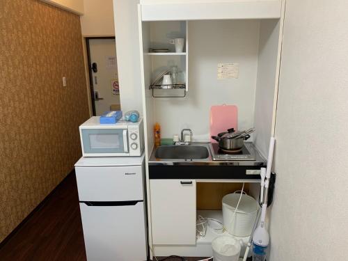 una pequeña cocina con fregadero y microondas en Exsaison Shirokita 201, en Osaka