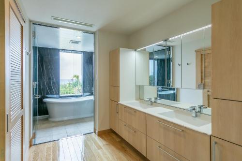 Miyakojima Kurima Resort Seawood Hotel في جزيرة مياكو: حمام به مغسلتين وحوض استحمام ومرآة