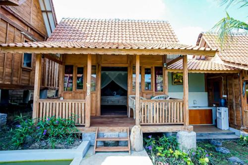una casa con portico in legno e tetto di Cening Bagus Bungalow a Canggu