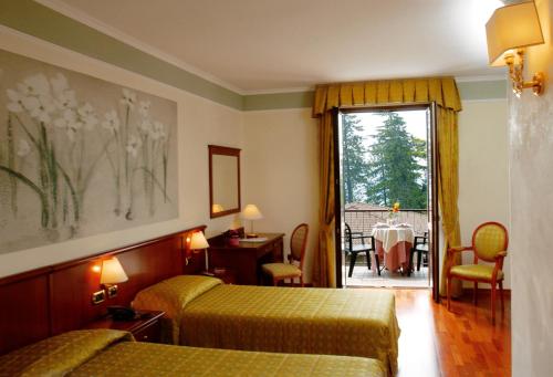 a hotel room with two beds and a table and a window at Hotel Astra in Tignale