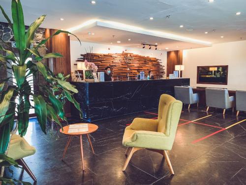 a lobby with chairs and a bar in the background at Lazenda Hotel in Labuan