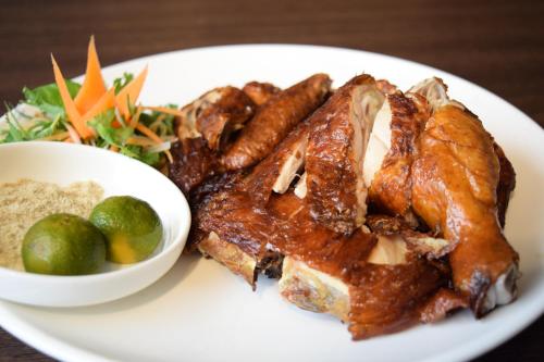 a plate of food with meat and a bowl of vegetables at Lazenda Hotel in Labuan