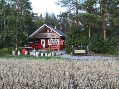 uma pequena casa com um parque infantil em frente em Maatilamatkailu Ilomäki em Peräseinäjoki