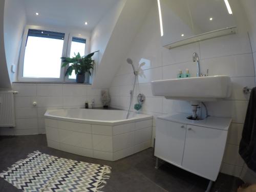 een witte badkamer met een wastafel, een bad en een wastafel bij modernes Penthouse, nahe Würzburg in Würzburg
