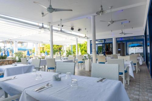 un restaurant avec des tables et des chaises blanches ainsi que des tables et des chaises blanches dans l'établissement Anonymous Beach Hotel (Adults 16+), à Ayia Napa