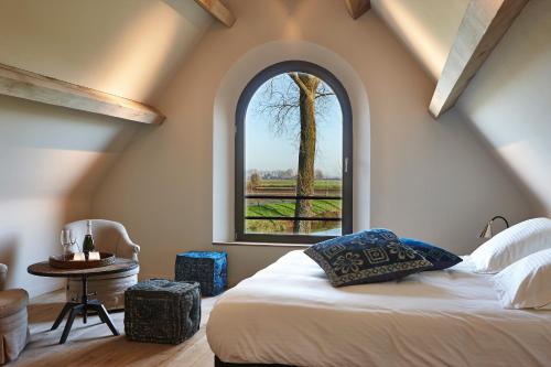 um quarto com uma cama e uma grande janela em De Zonnebrug Landhuis em Sint-Laureins