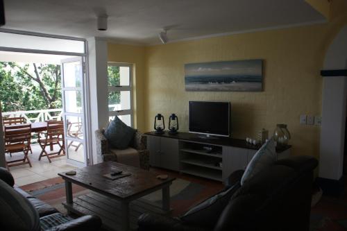 a living room with a couch and a television at The Villa at Caribbean Estates in Port Edward